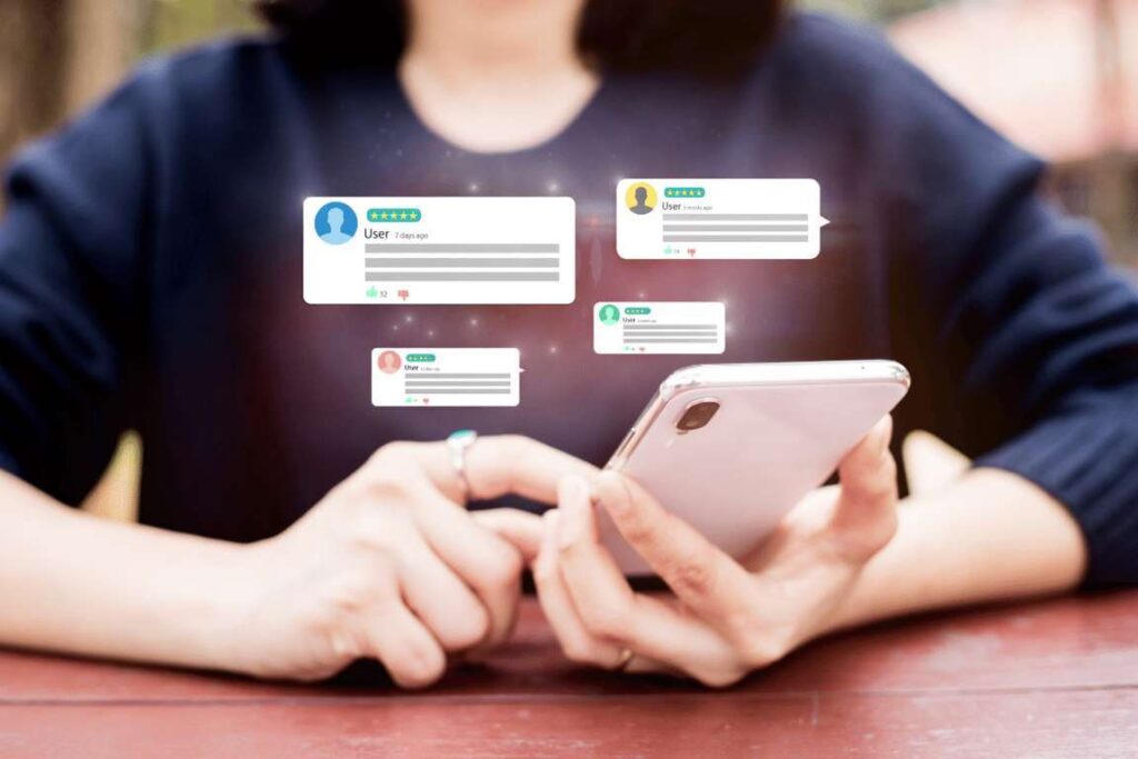 Persona che utilizza uno smartphone con varie notifiche di recensioni dei clienti che gli fluttuano tra le mani.