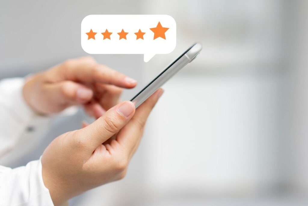 Una persona tiene in mano uno smartphone con una bolla di valutazione a cinque stelle che appare sopra lo schermo.